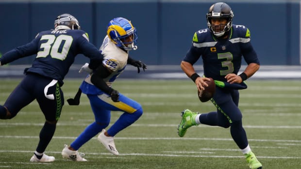 Jan 9, 2021; Seattle, Washington, USA; Seattle Seahawks quarterback Russell Wilson (3) rolls out of the pocket while pressured by Los Angeles Rams cornerback Troy Hill (22) during the second quarter at Lumen Field.